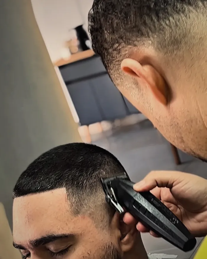 Máquina fazendo a transição do degradê na lateral da cabeça de um cliente