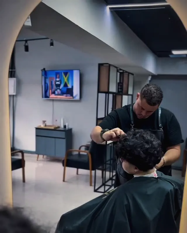 Interior do Studio Wolver, com o barbeiro atendendo um cliente na cadeira