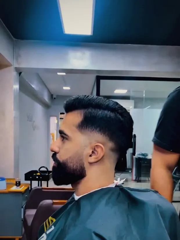 Cliente de perfil com a barba alinhada e o degradê finalizado