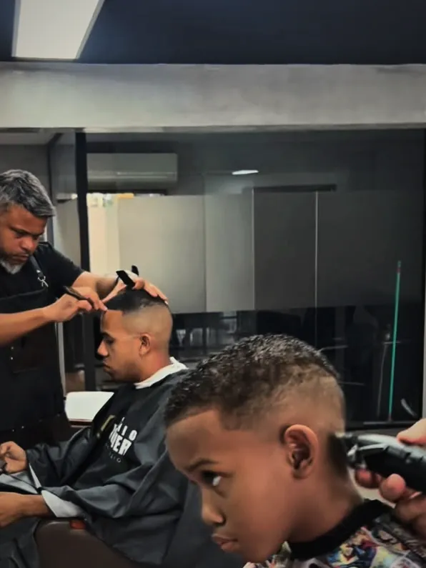 Criança sendo atendida na cadeira do Studio Wolver ao lado do pai