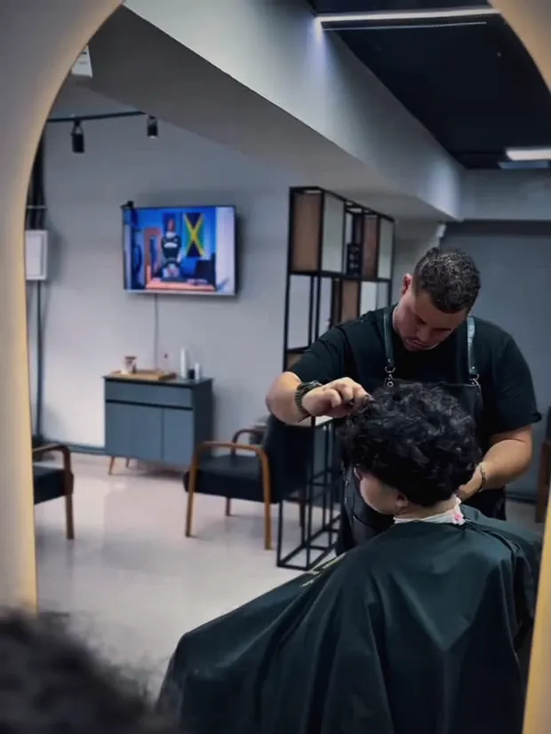 Barbeiro cortando o cabelo na tesoura no salão do Studio Wolver